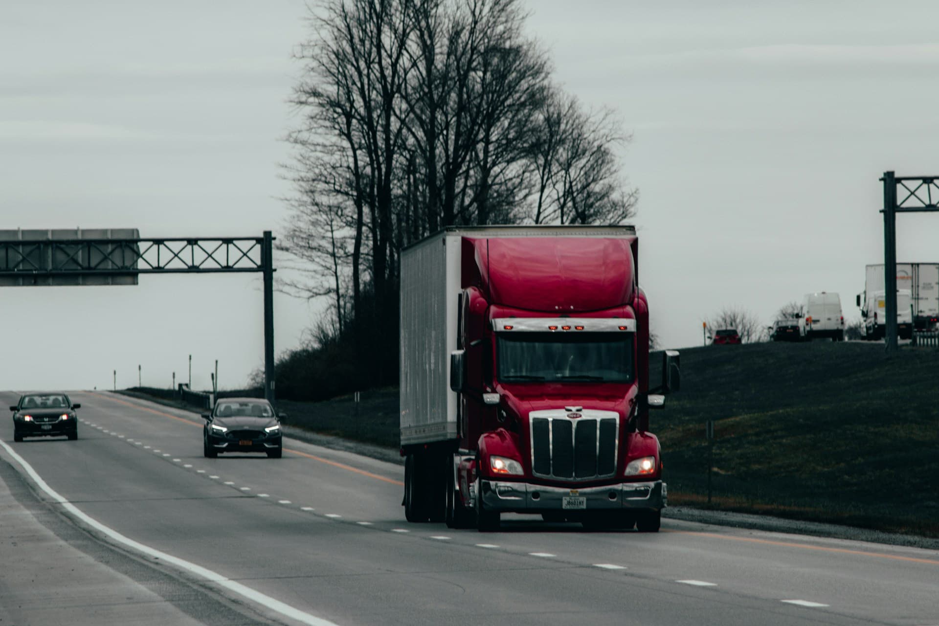 Red semi tractor pulling a dry van trailer down a US highway